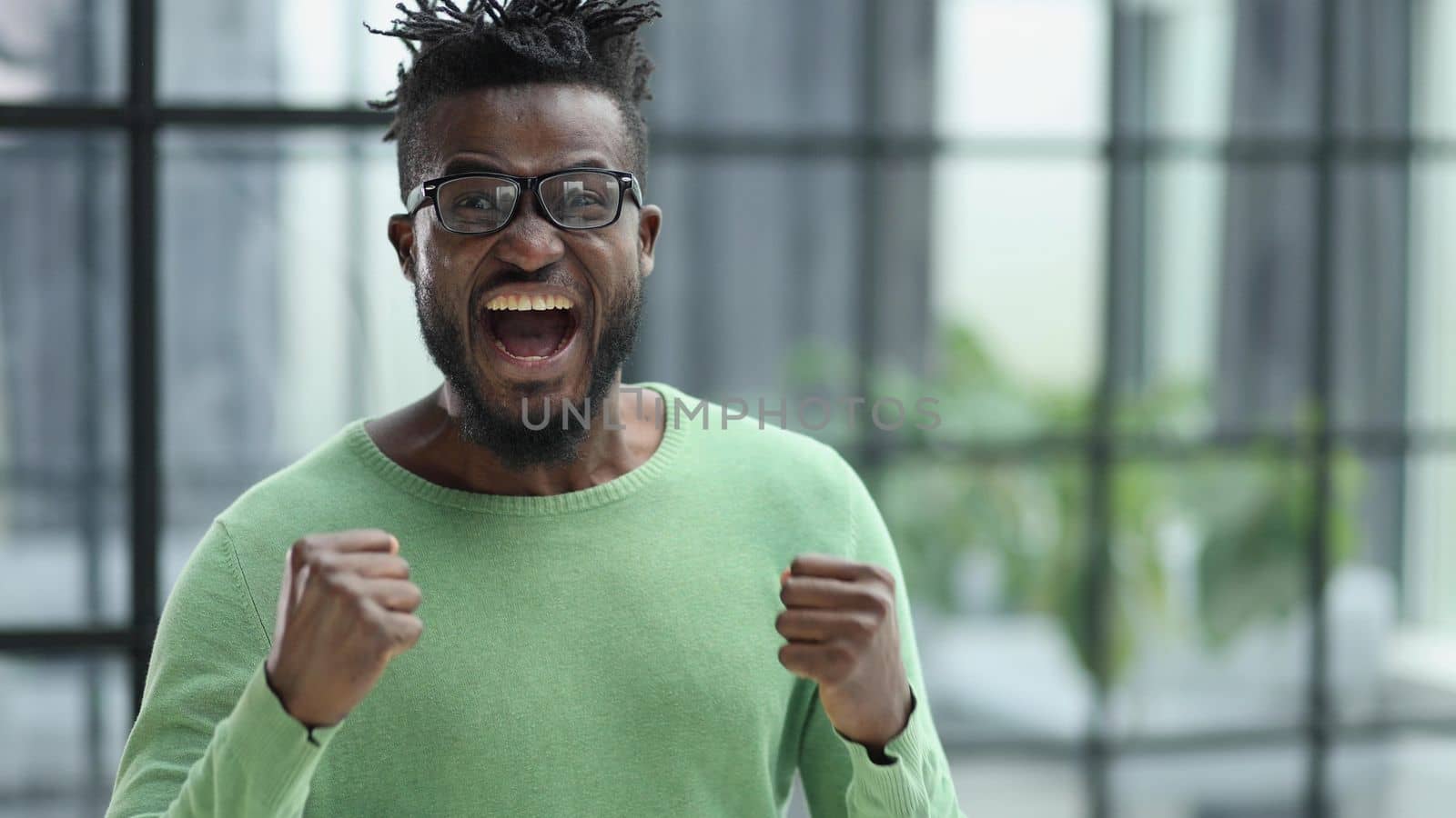 Winning ecstatic young African man clenching his fists with excited face