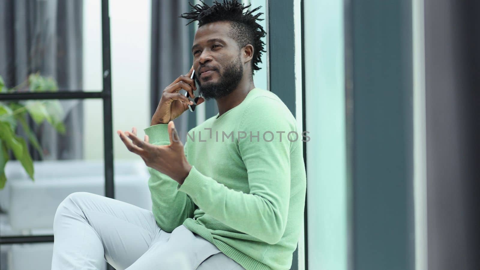 Smiling young adult african american hipster business man professional making business call talking on the phone