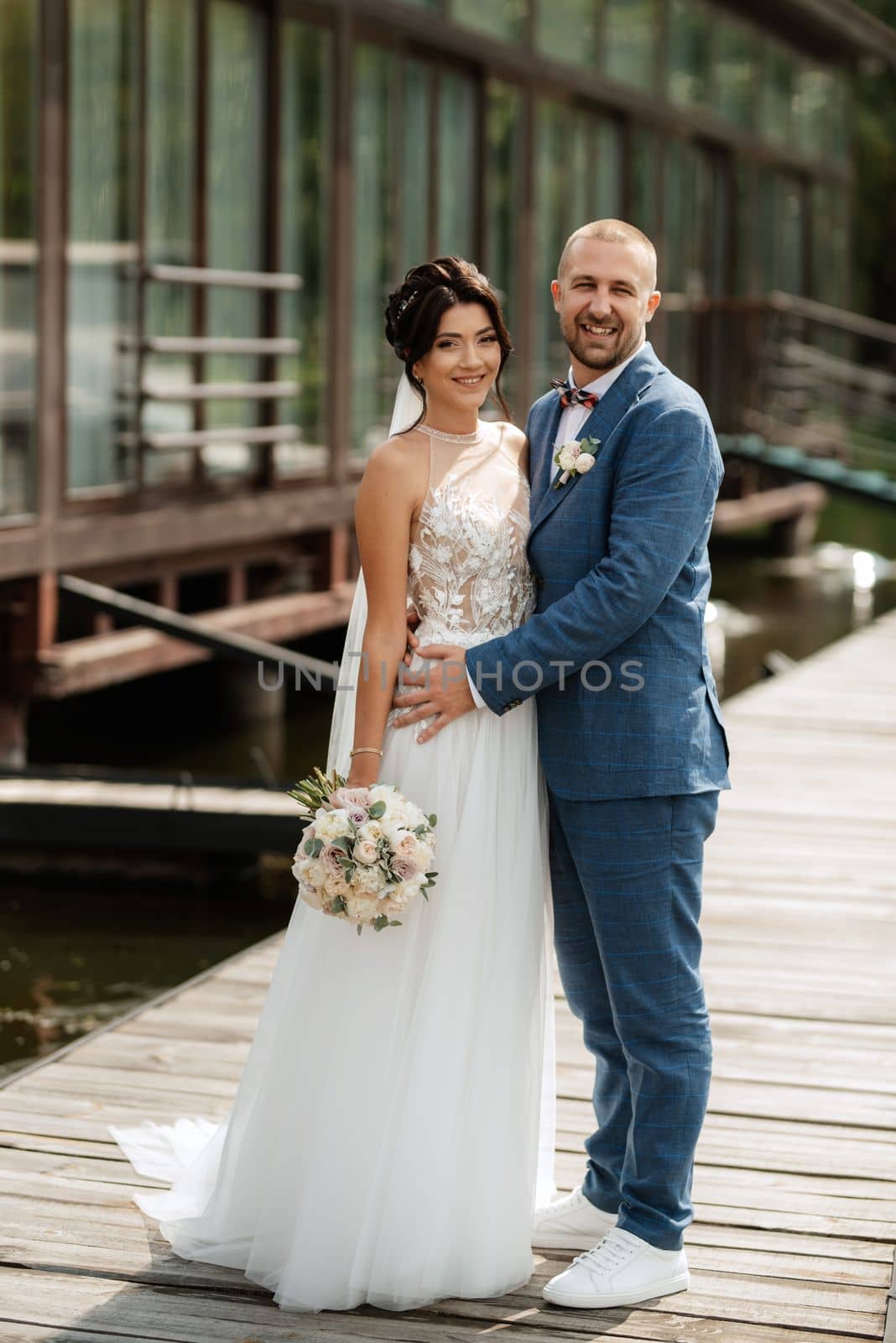 the first meeting of the bride and groom in wedding dresses on the pier near the water