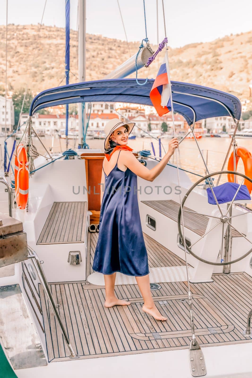 Woman yacht sea. Young happy woman in a blue dress and hat on a yacht. Travel and vacation concept.
