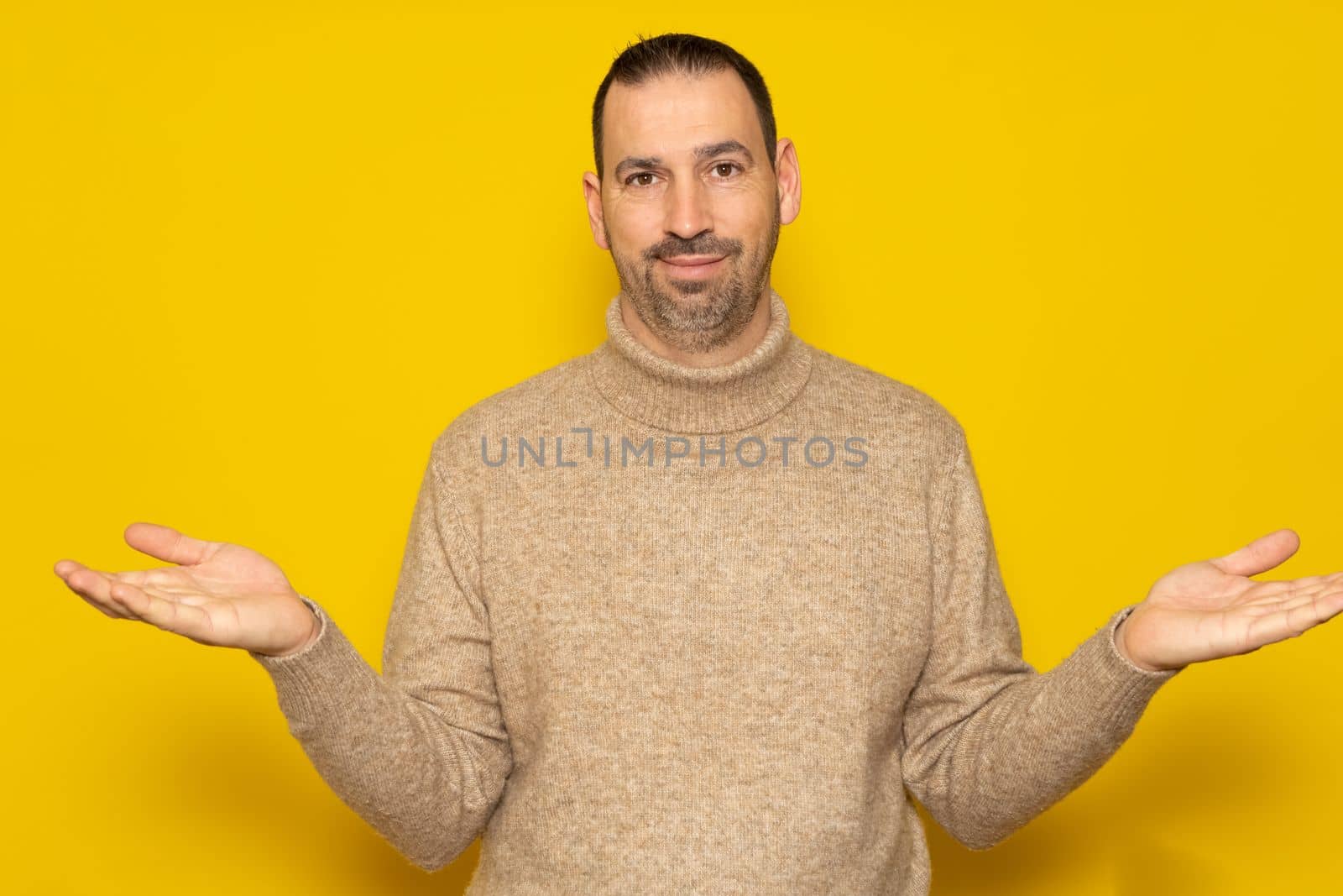 So what, who cares. Unsure and doubtful hispanic man with a beard wearing a beige turtleneck sweater isolated over yellow background. Indecision concept by Barriolo82