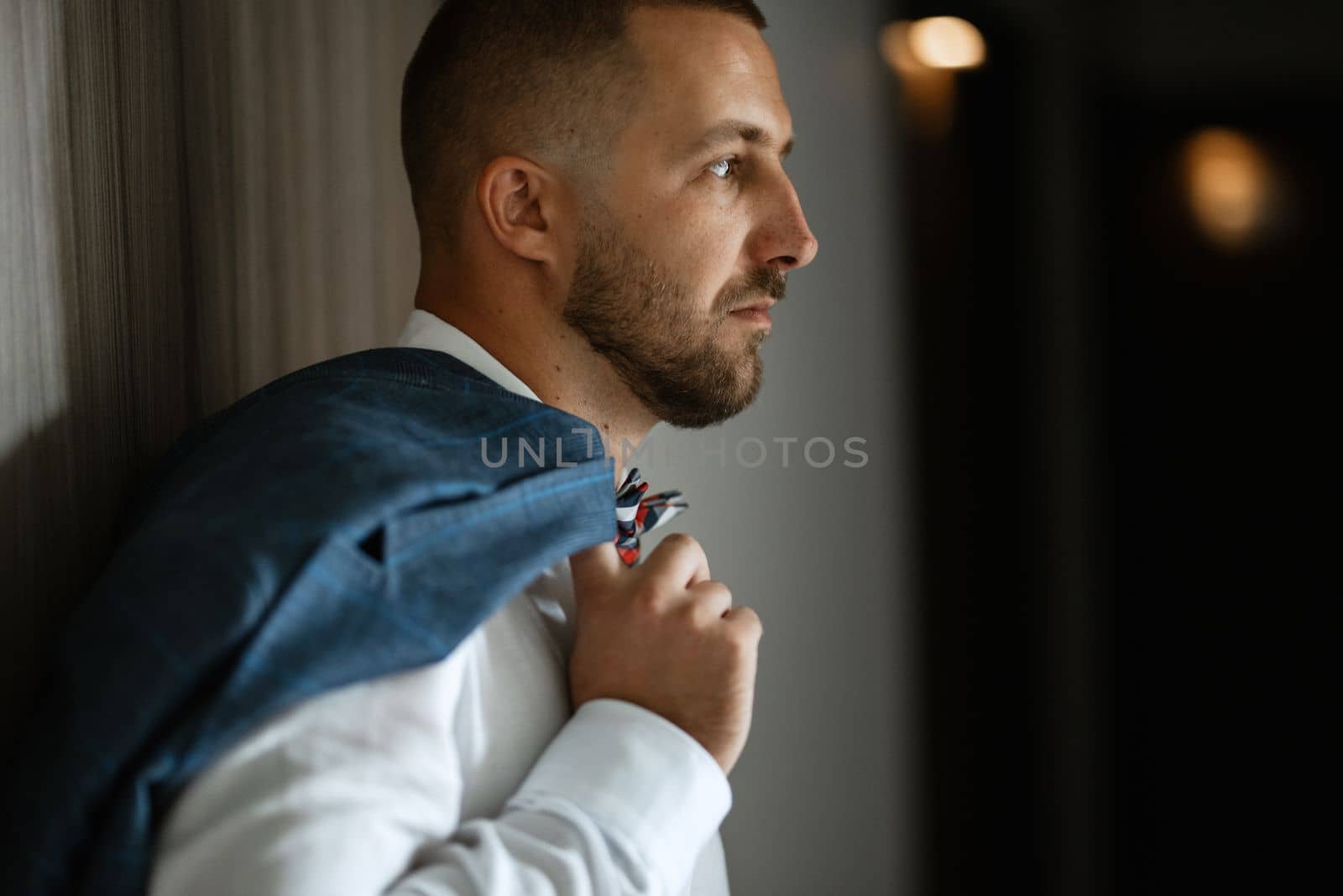 portrait of smiling groom with beard in blue color suit