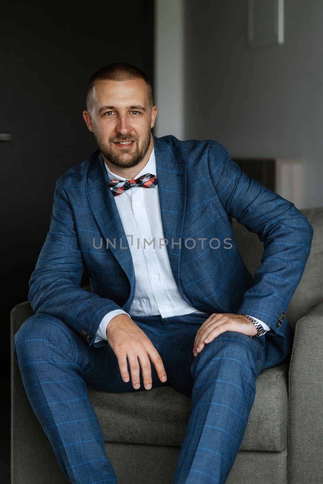 portrait of smiling groom with beard in blue color suit