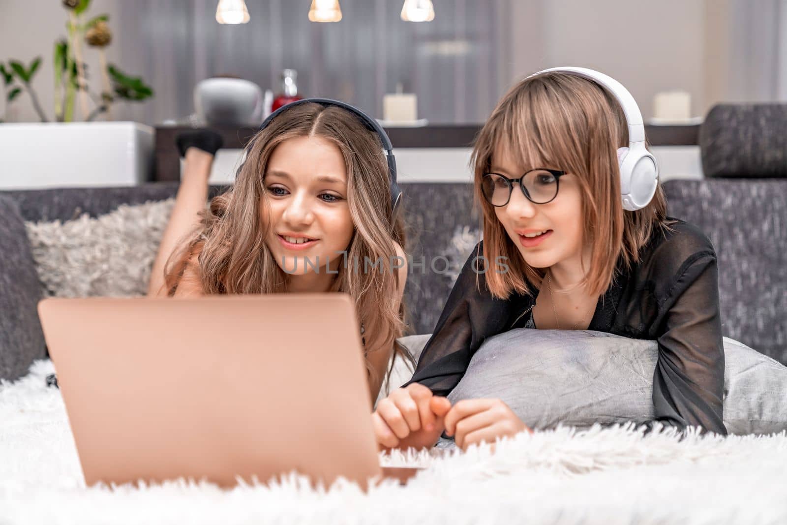 children with wireless headphones on their heads enjoy internet entertainment online on a laptop at home. High quality photo