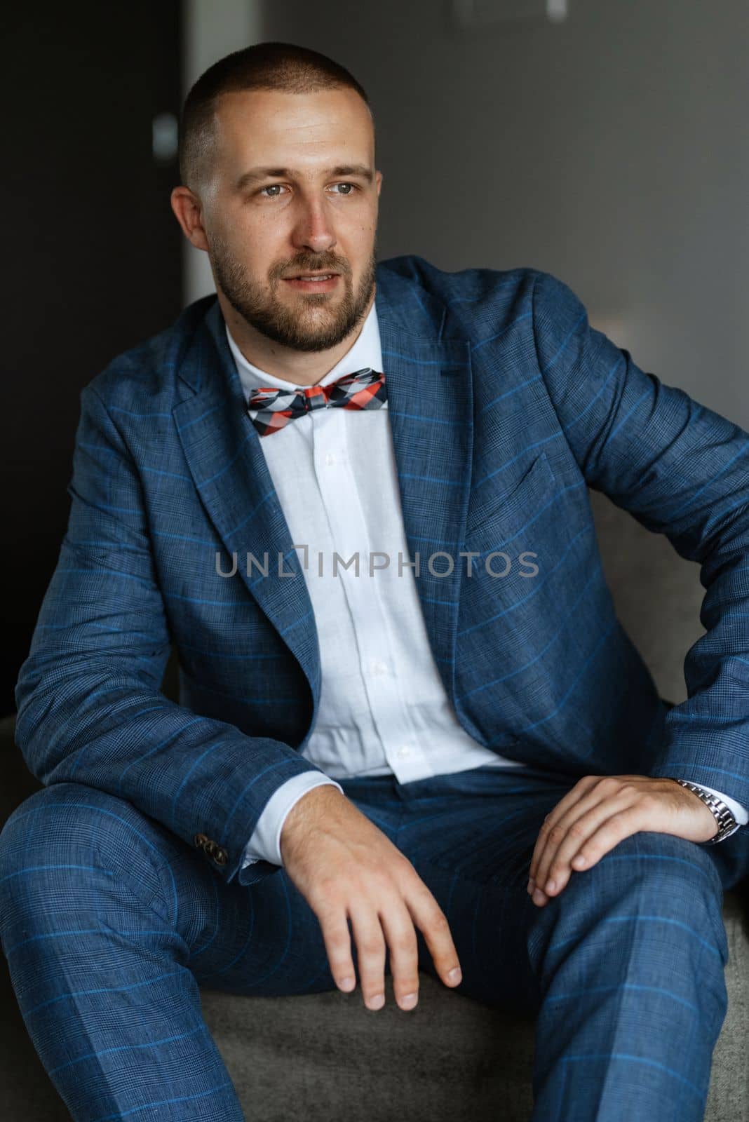 portrait of smiling groom with beard in blue color suit