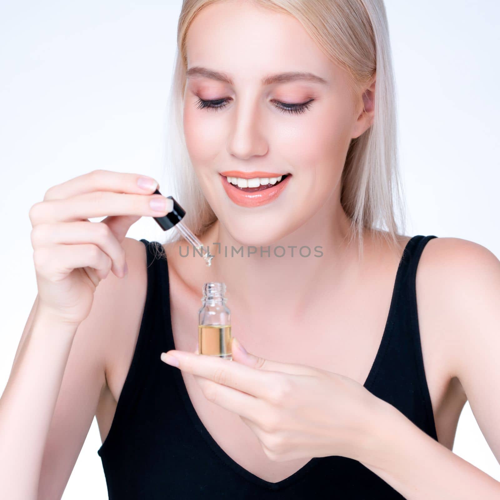 Personable closeup woman with natural makeup applying essential serum oil bottle for skincare product. CBD oil dropper pipette for cosmetology treatment and cannabinoids concept in isolated background
