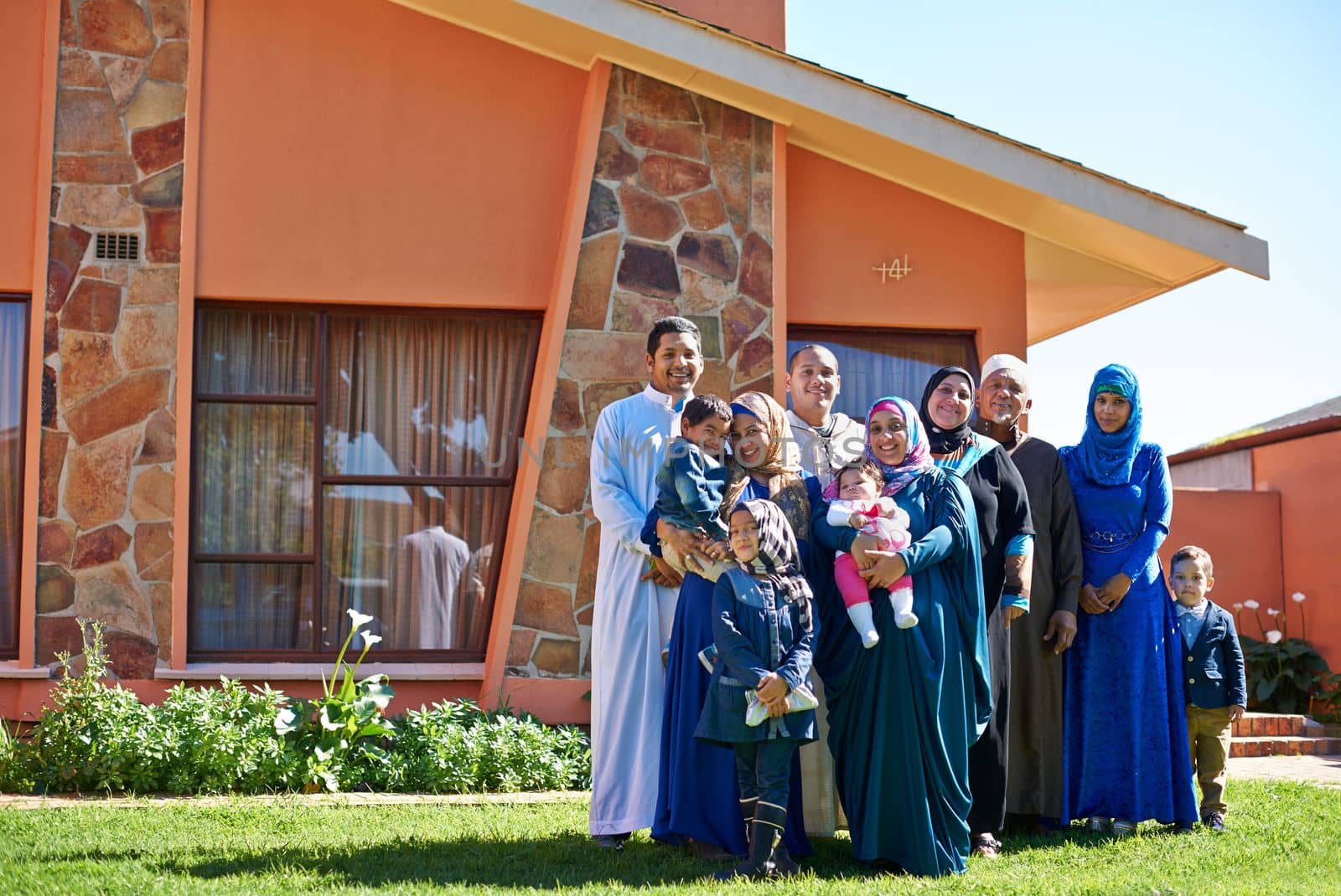 Were a family full of love. Portrait of a happy muslim family standing together in front of their house. by YuriArcurs