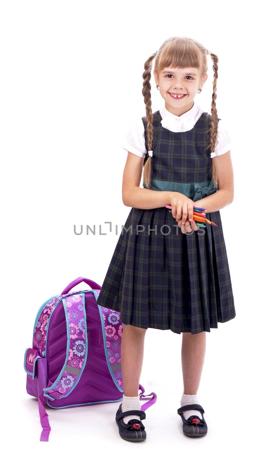 A giggling schoolgirl. Adorable little schoolgirl with happy smile keeping arms crossed. Small schoolgirl looking nice in school uniform. Cute schoolgirl with long brunette hair and charming look.