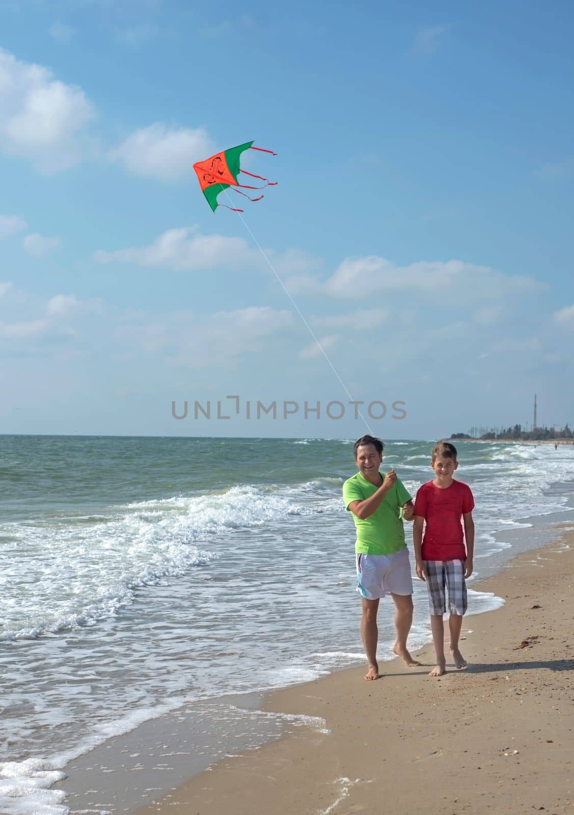 Rest of parents with children. Dad and son fly a kite near the sea