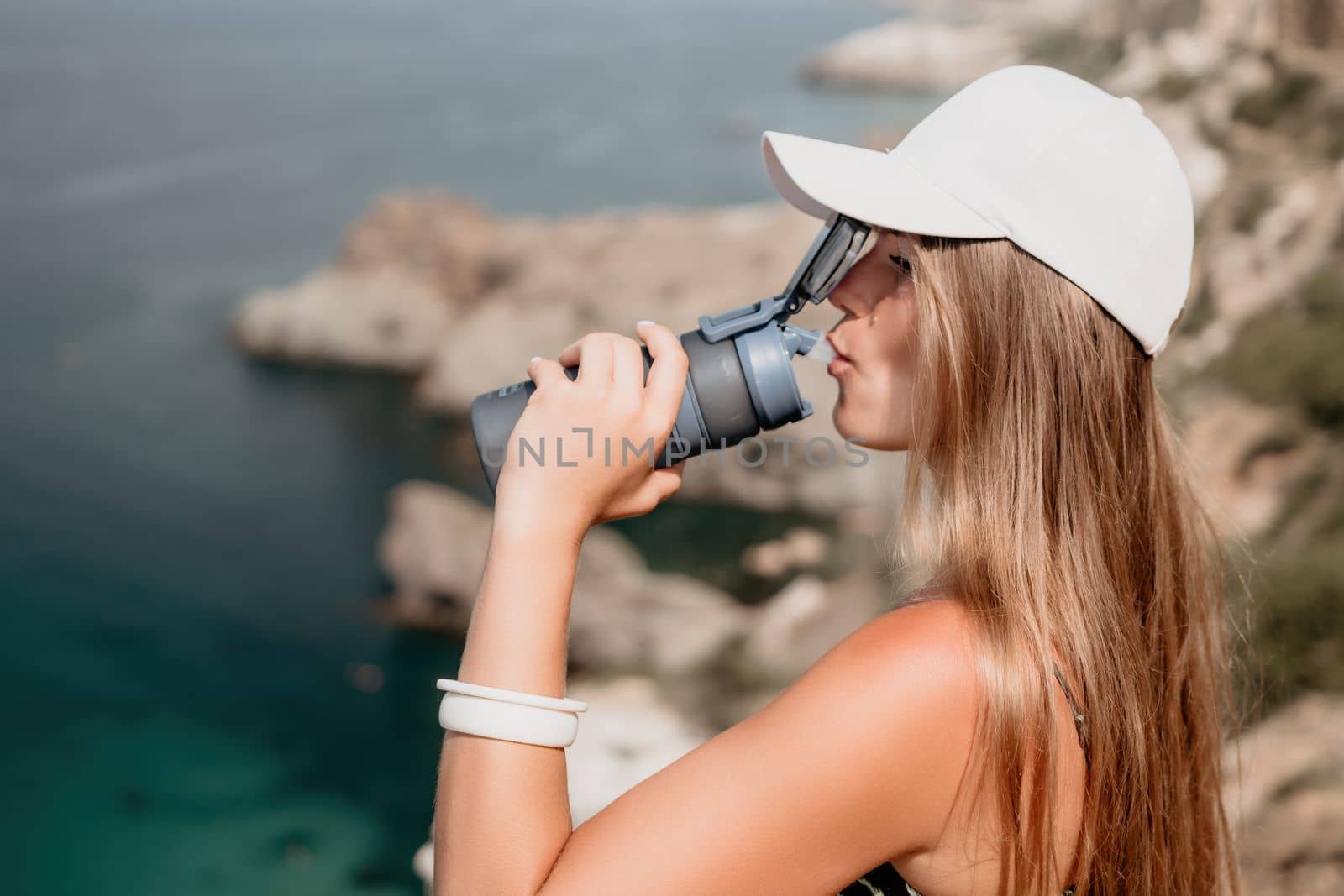 Woman travel sea. Happy tourist taking picture outdoors for memories. Woman traveler looks at the edge of the cliff on the sea bay of mountains, sharing travel adventure journey.