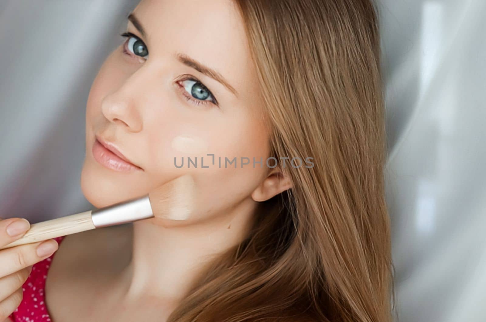 Beautiful woman applying liquid make-up foundation on her skin with make-up brush by Anneleven