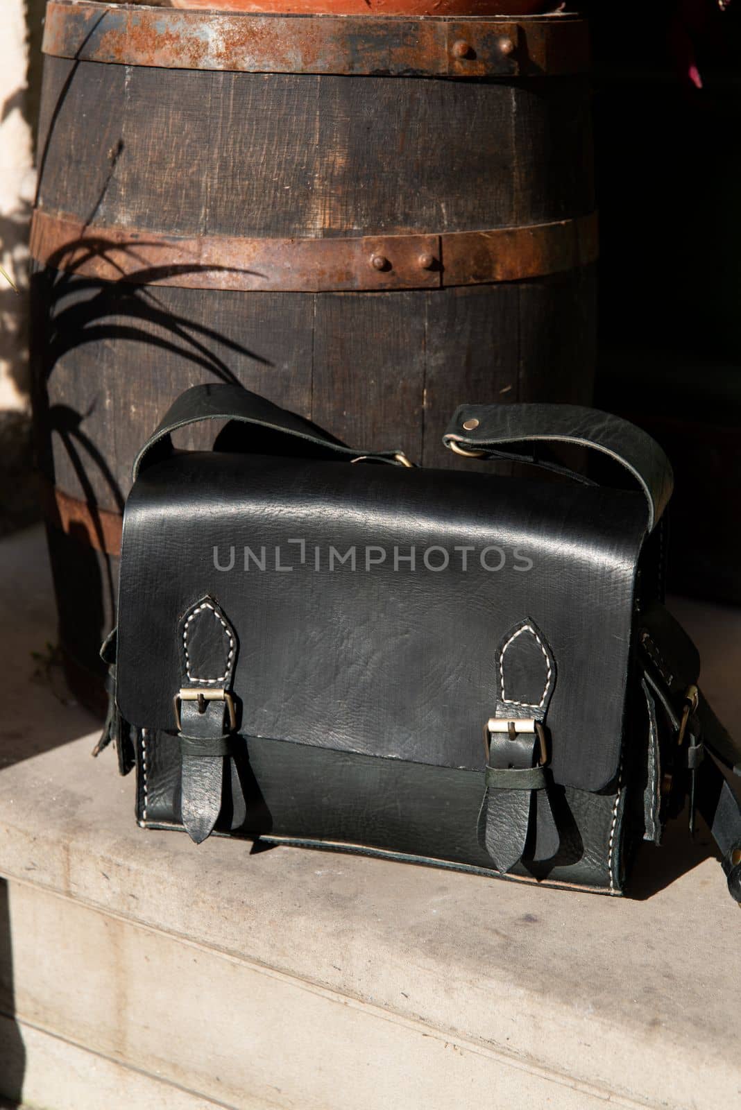 close-up photo of black leather bag corporate. a photo of a briefcase near an old wooden barrel by Ashtray25