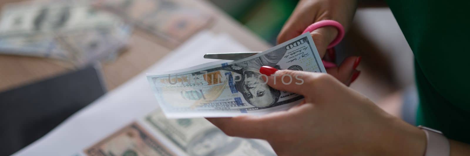 Female hand cuts counterfeit money American dollars. Difference between counterfeit banknotes and fake banknotes