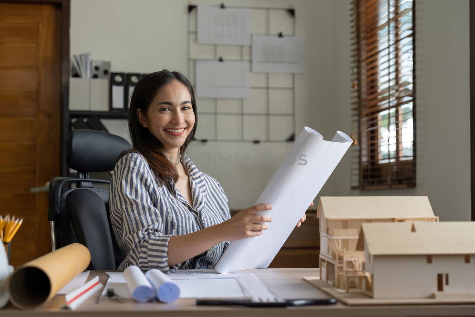 Female asian architect working on blueprint at office