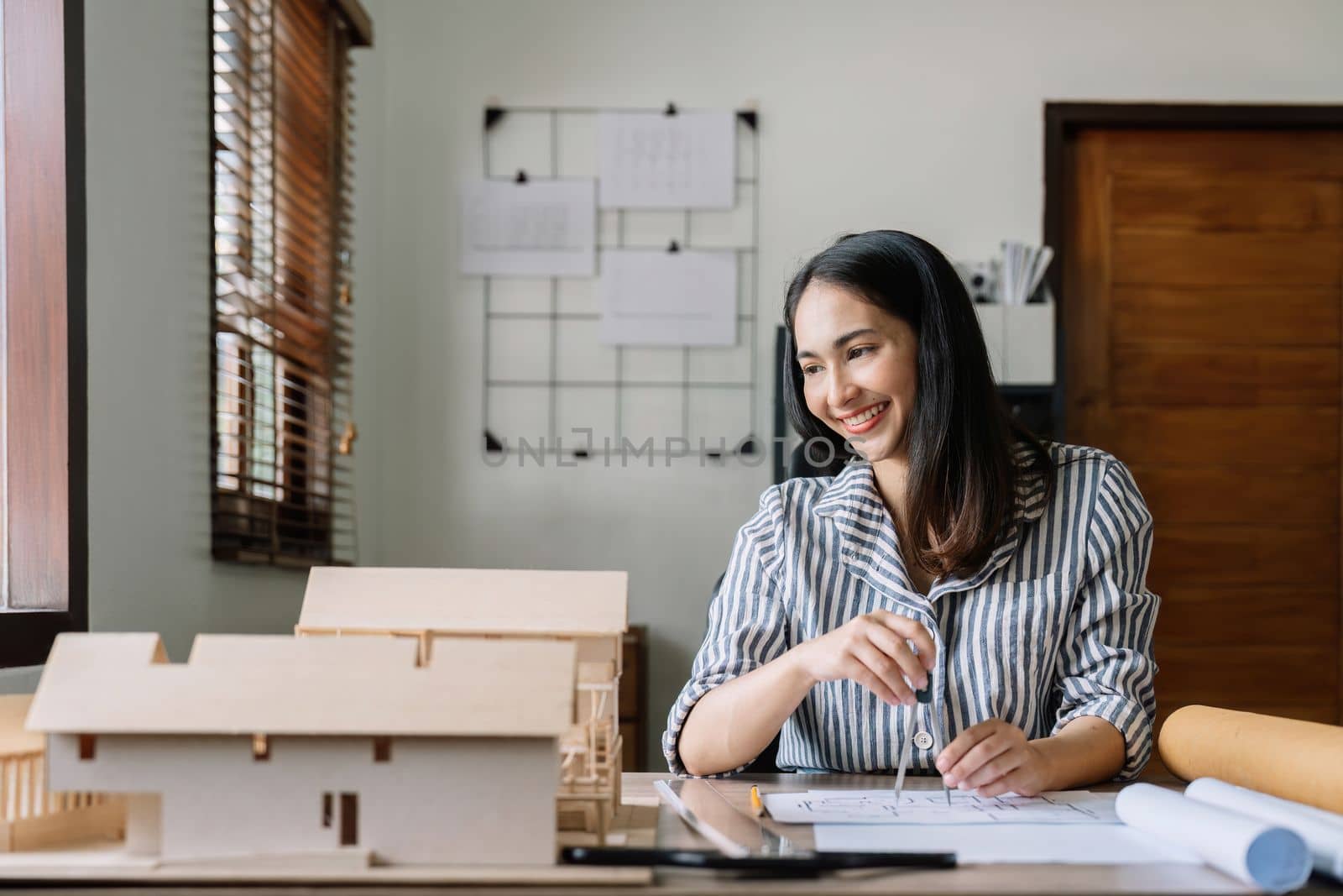 Female asian architect working on blueprint at office
