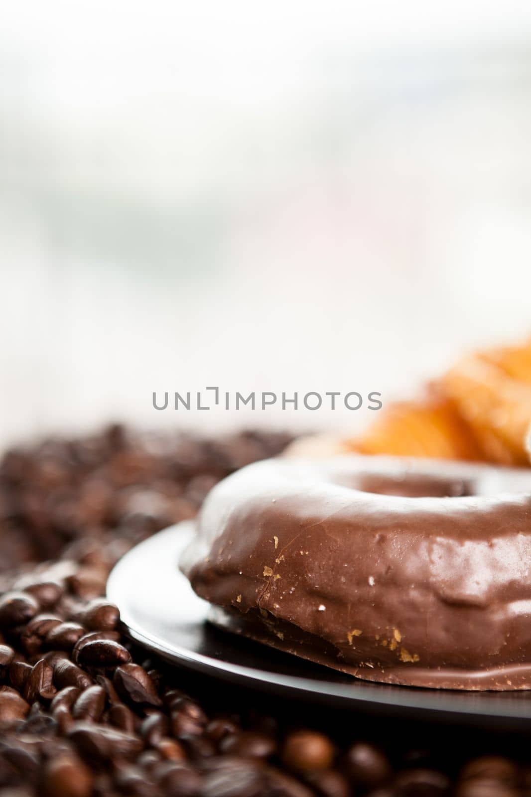 Coffee beans, donut and a cup of coffee in close up photo