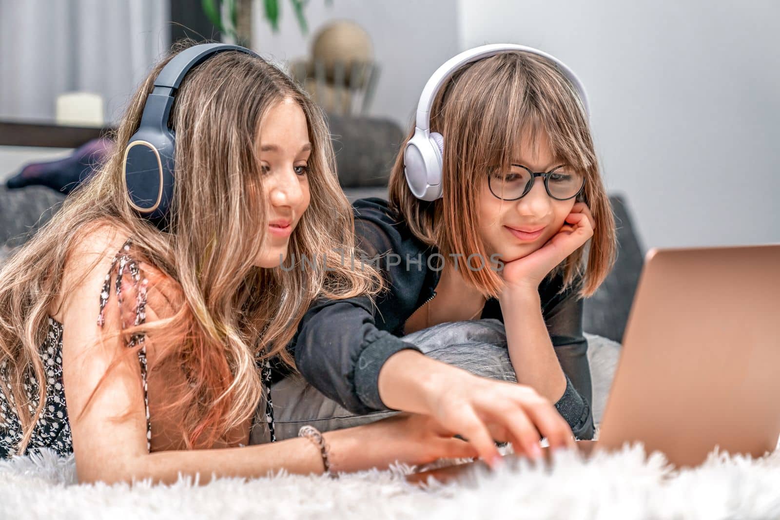 children with wireless headphones on their heads enjoy internet entertainment online on a laptop at home. High quality photo