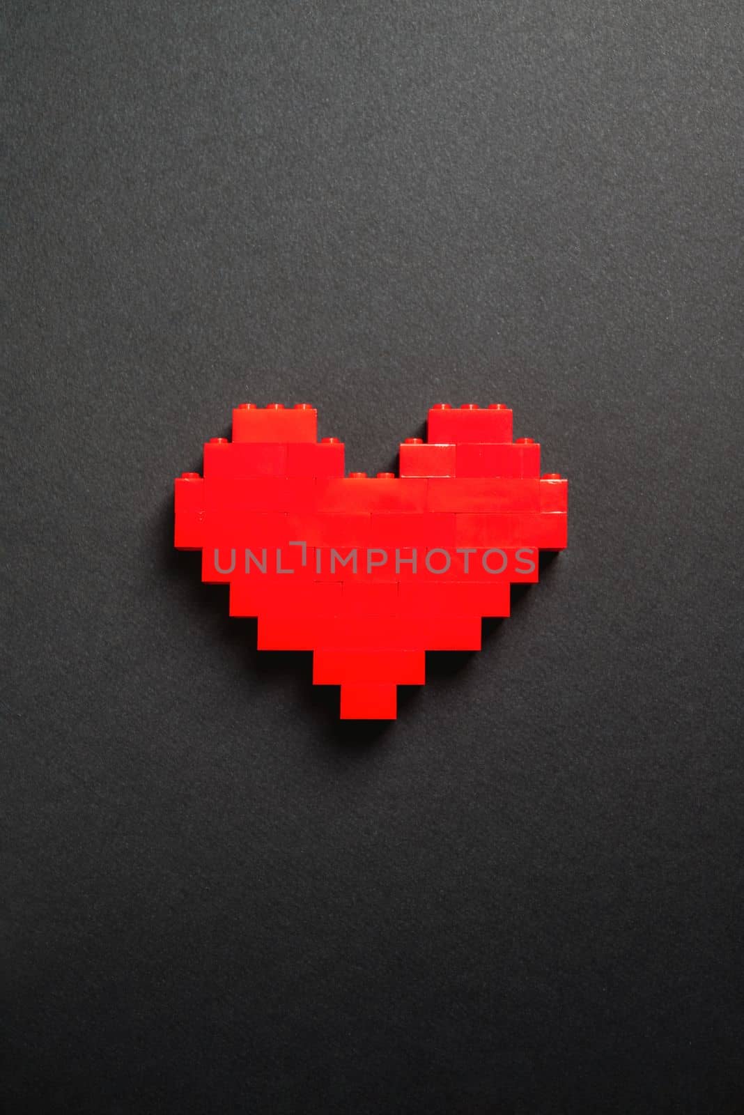 Red heart made of plastic bricks on a dark gray background