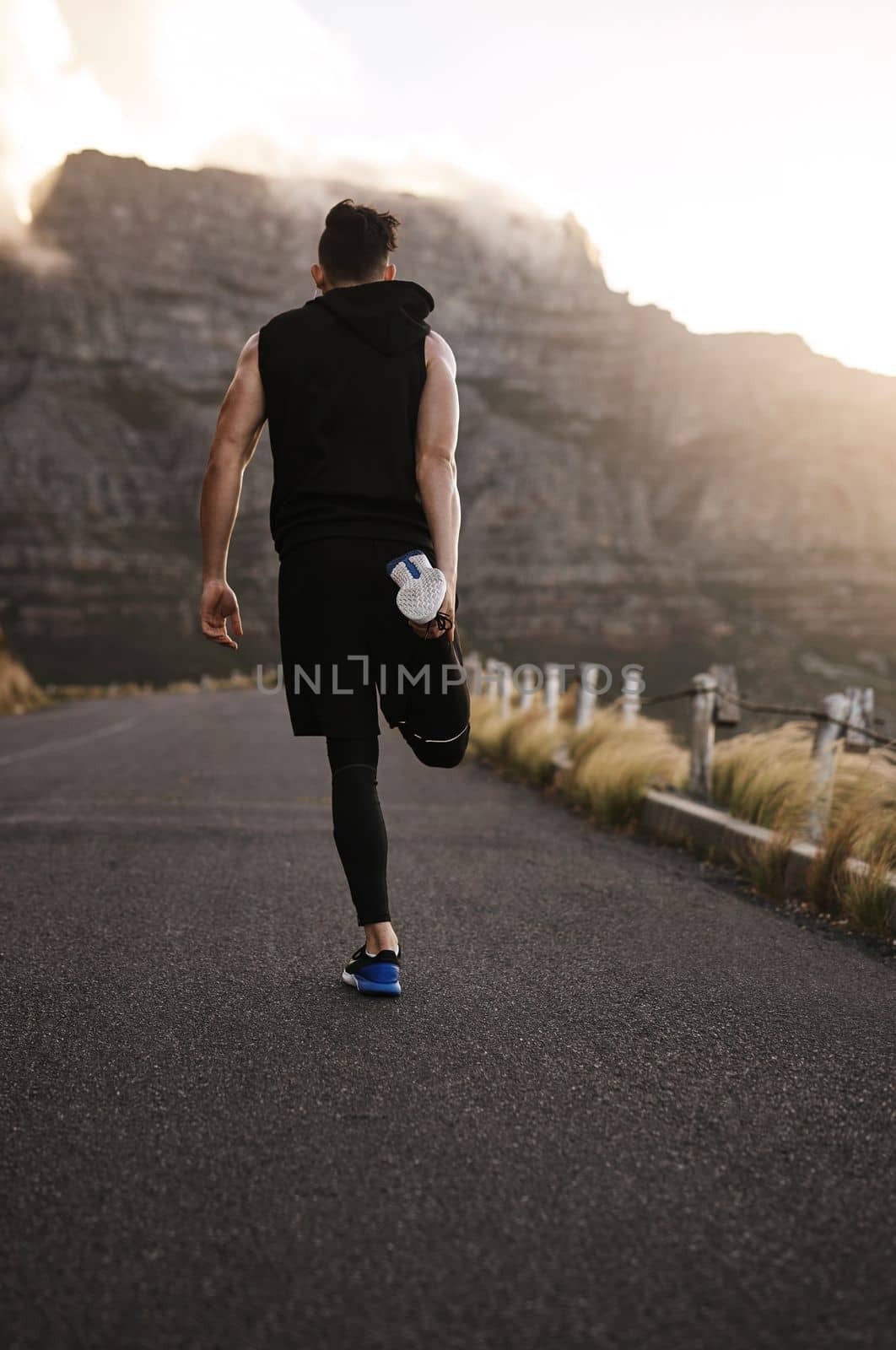 Its just you against yourself. Rearview shot of a sporty young man exercising outdoors. by YuriArcurs