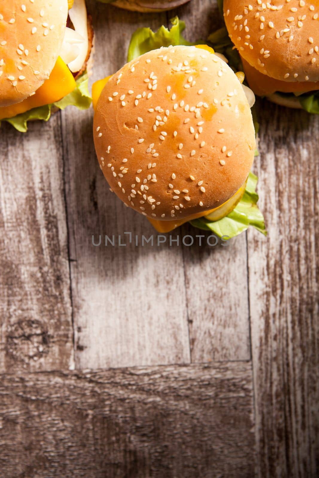Delicious tasty burgers on wooden background by DCStudio