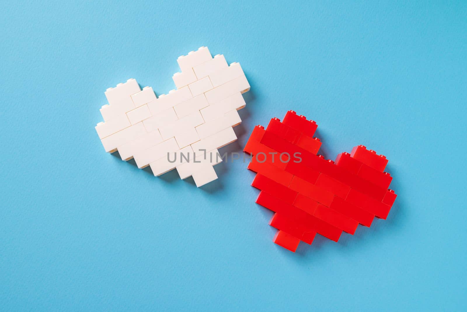 Red and white heart made of plastic bricks on a blue background