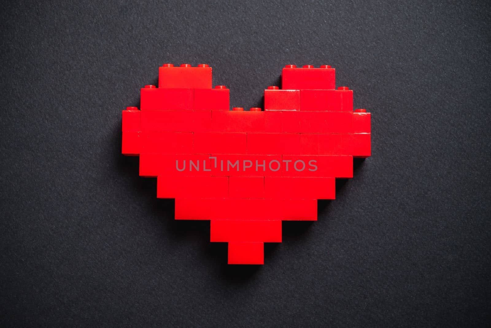 Red heart made of plastic bricks on a dark gray background by Sonat