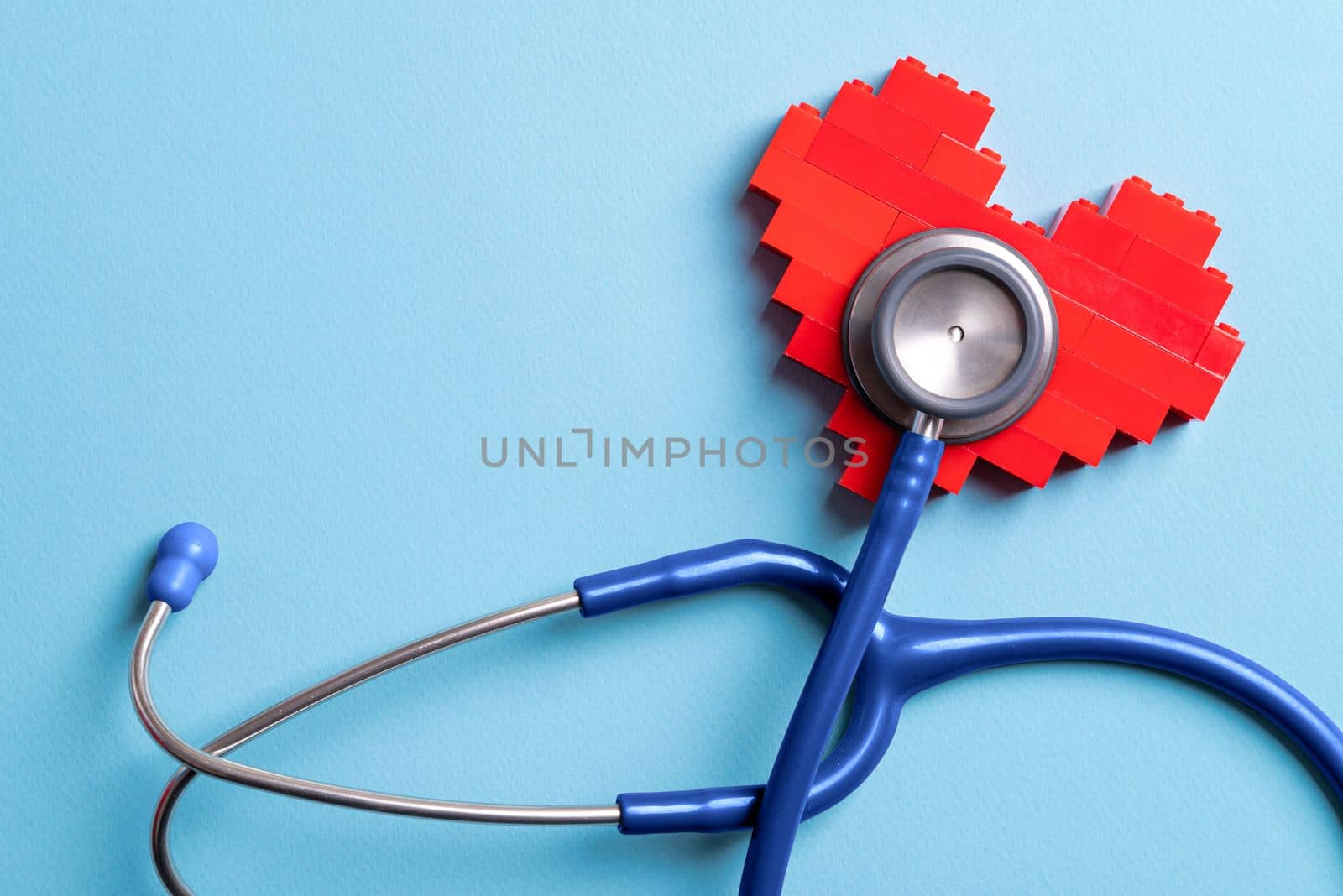 Blue stethoscope standing on red heart on blue background by Sonat