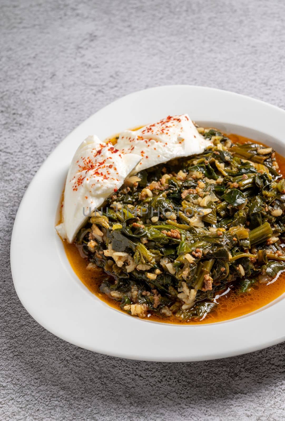 Traditional Turkish spinach meal with rice and minced meat with yogurt on a white porcelain plate