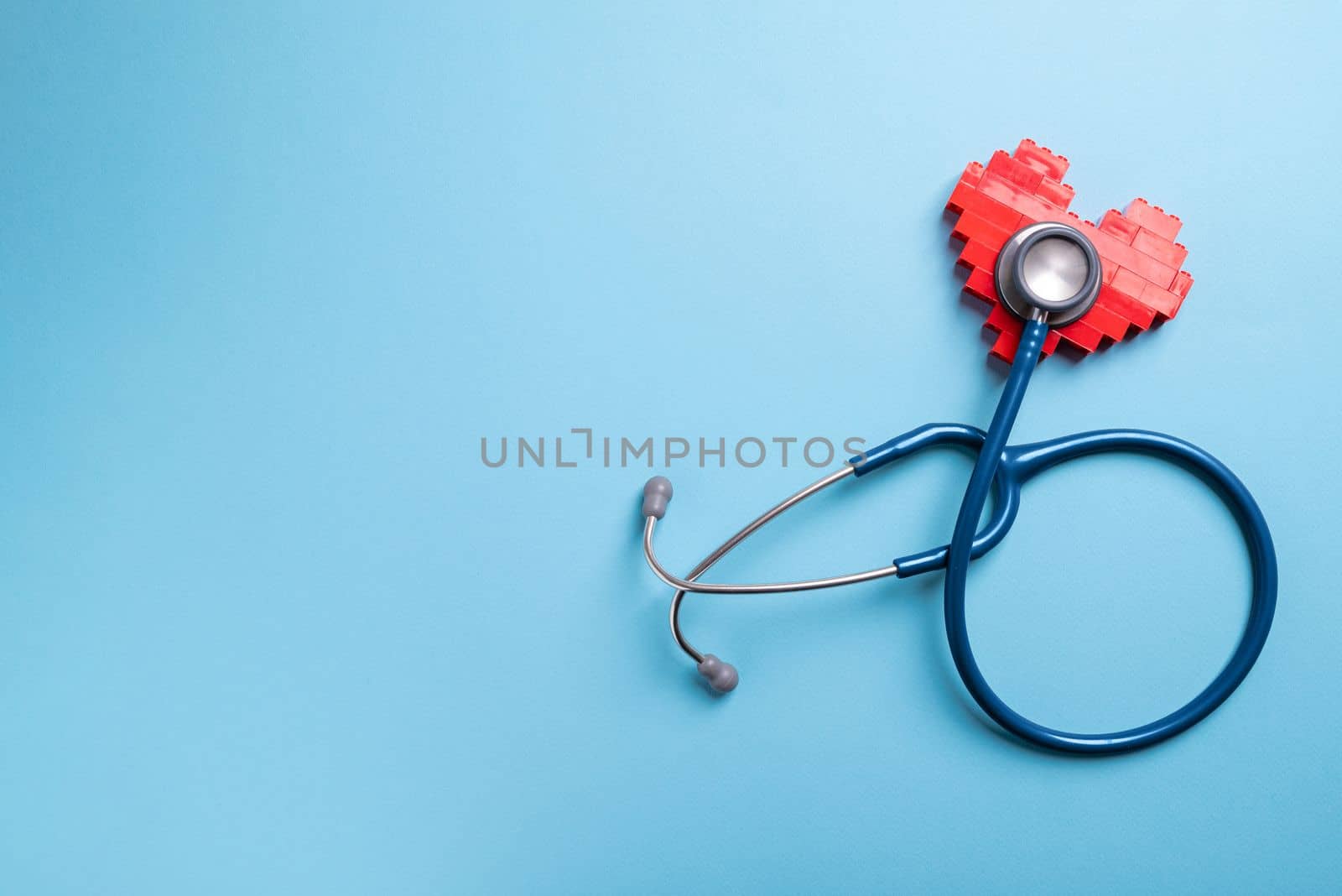 Blue stethoscope standing on red heart on blue background by Sonat