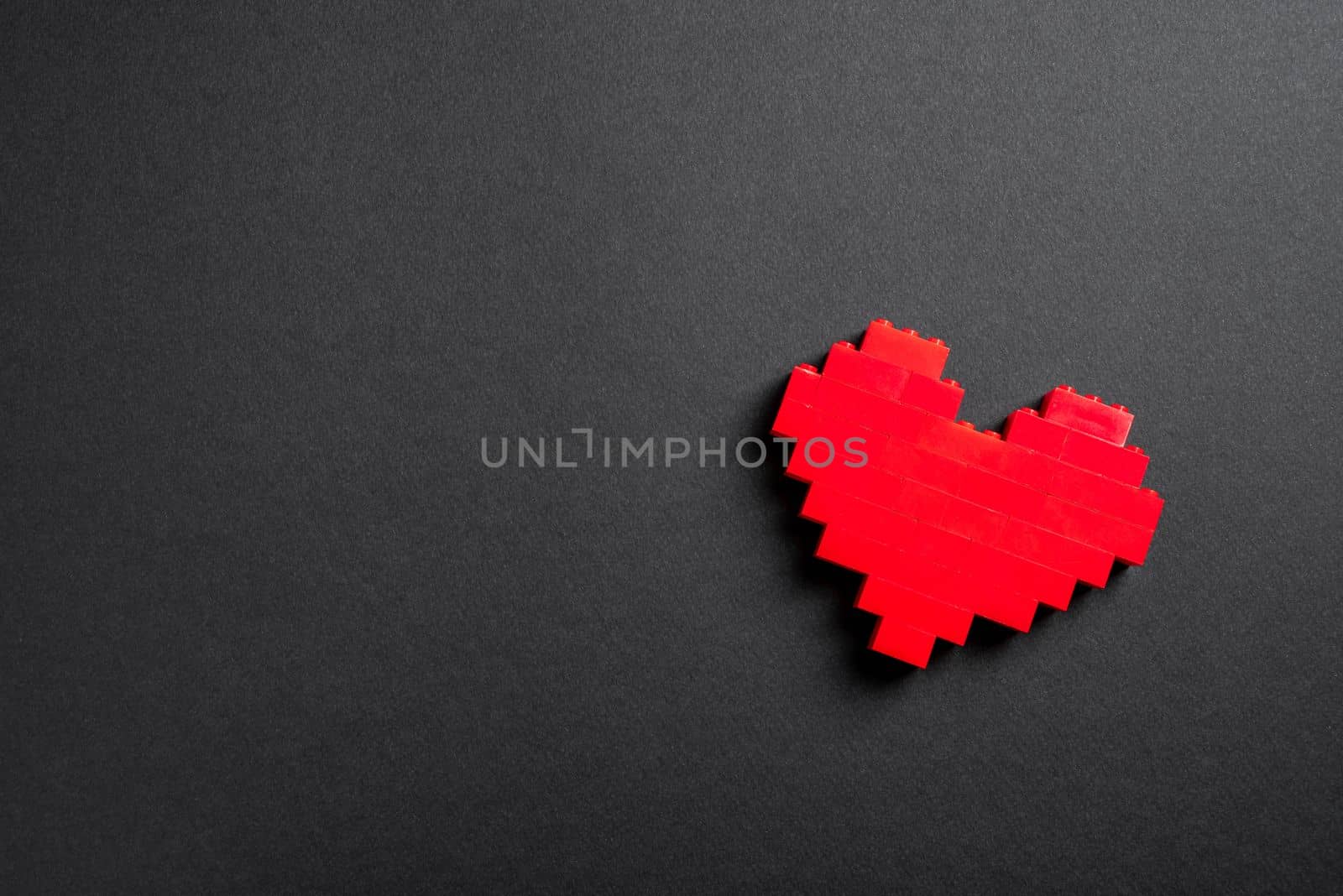 Red heart made of plastic bricks on a dark gray background by Sonat