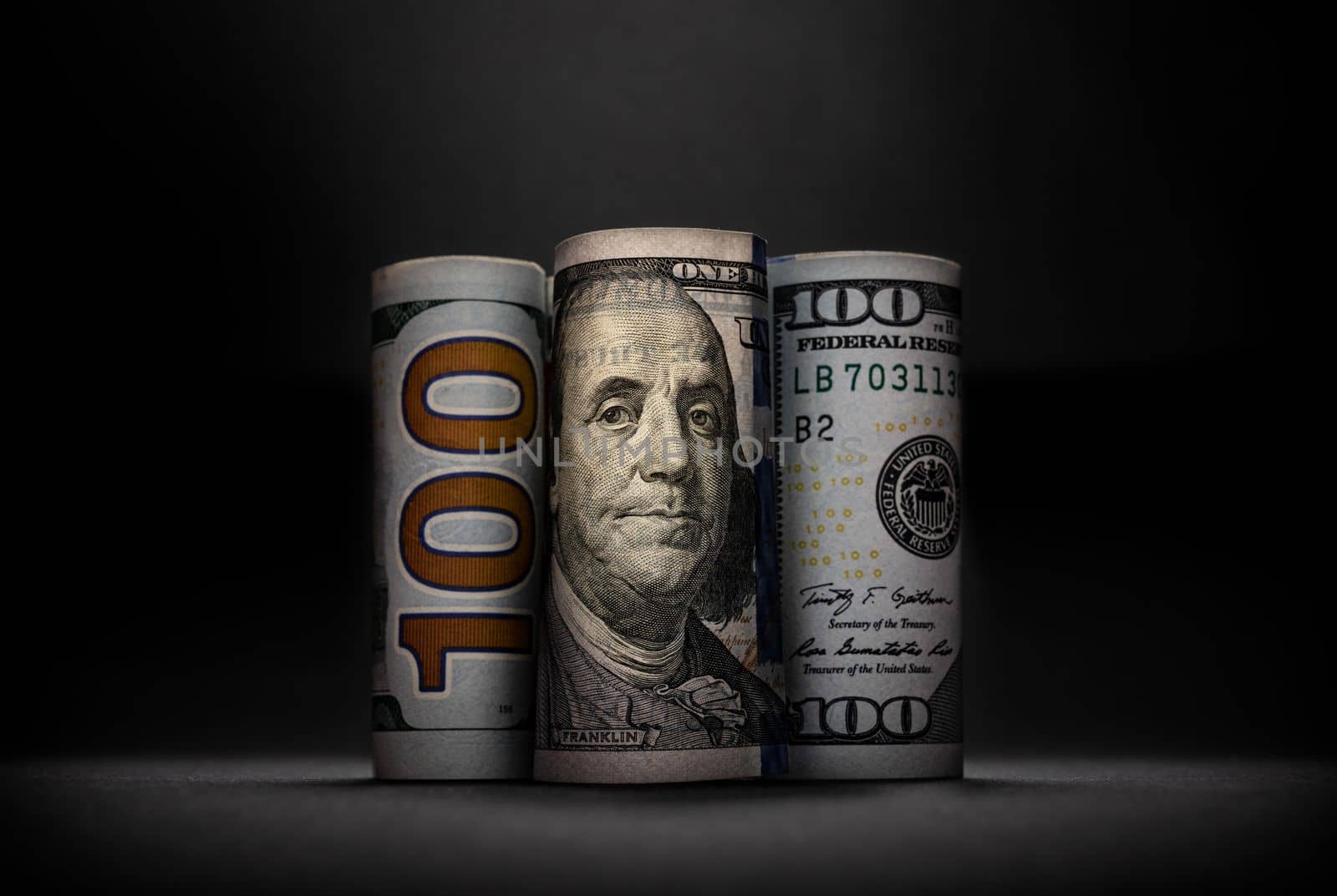 Three different images of 100 US dollars in rolls on dark background by Sonat
