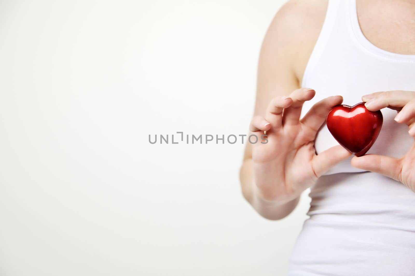 health, medicine and charity concept close up of female hands with small red heart holding for breast on white background copy space by Annebel146