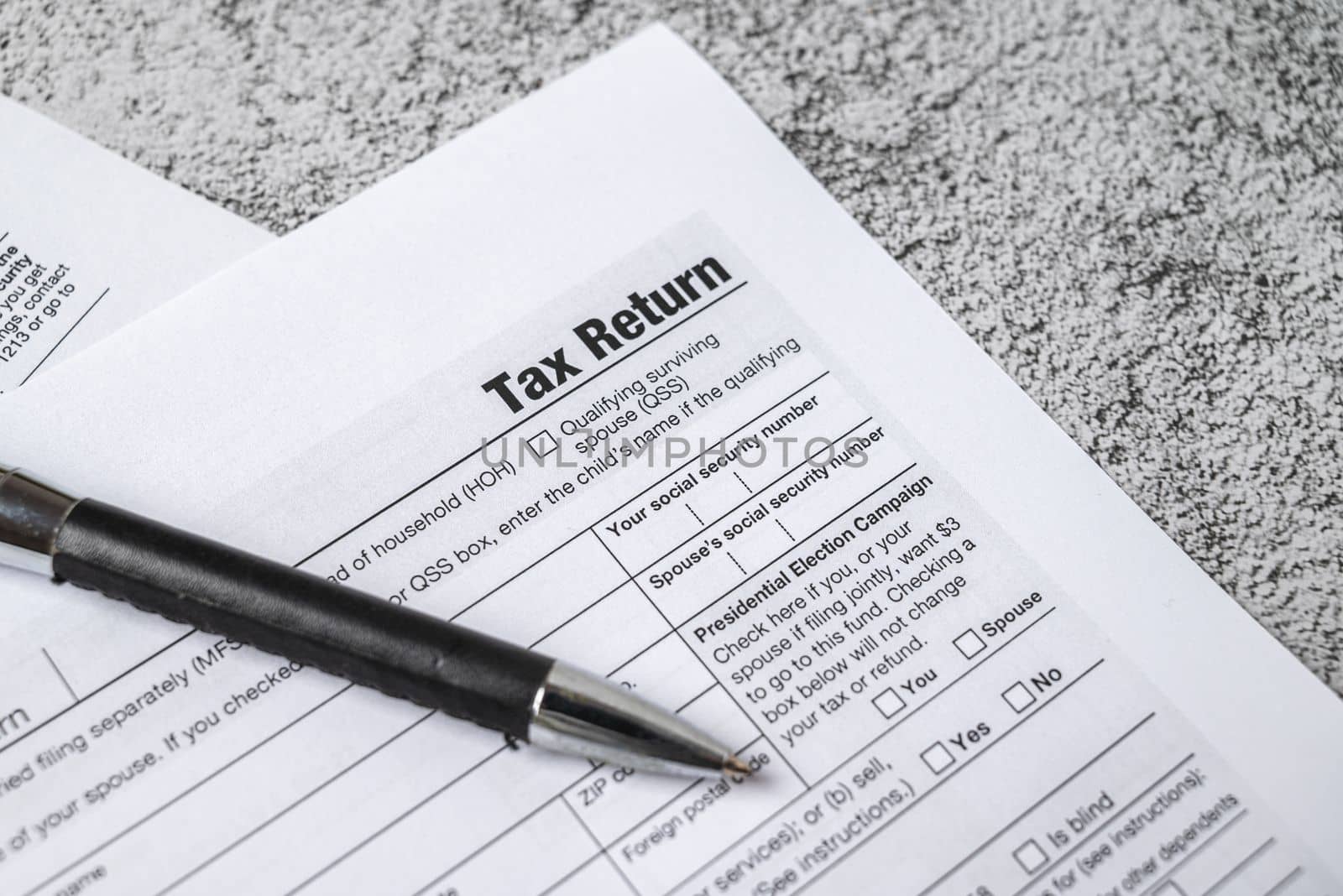 Financial time tax return forms with pen on stone table