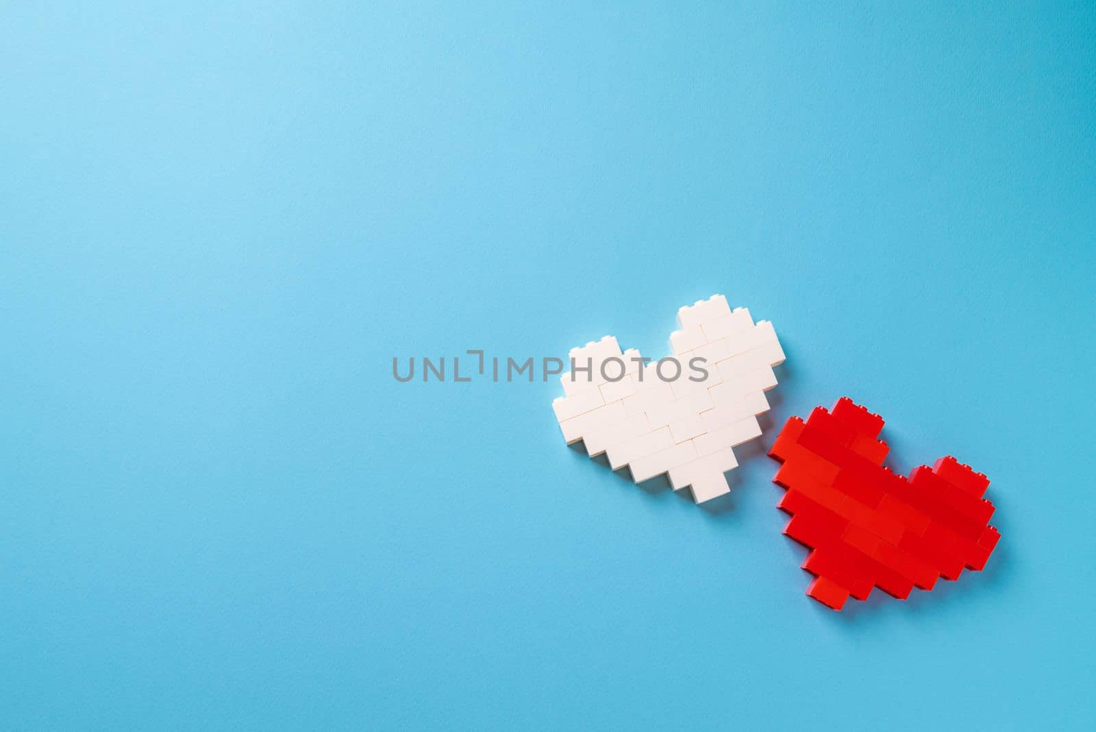 Red and white heart made of plastic bricks on a blue background by Sonat