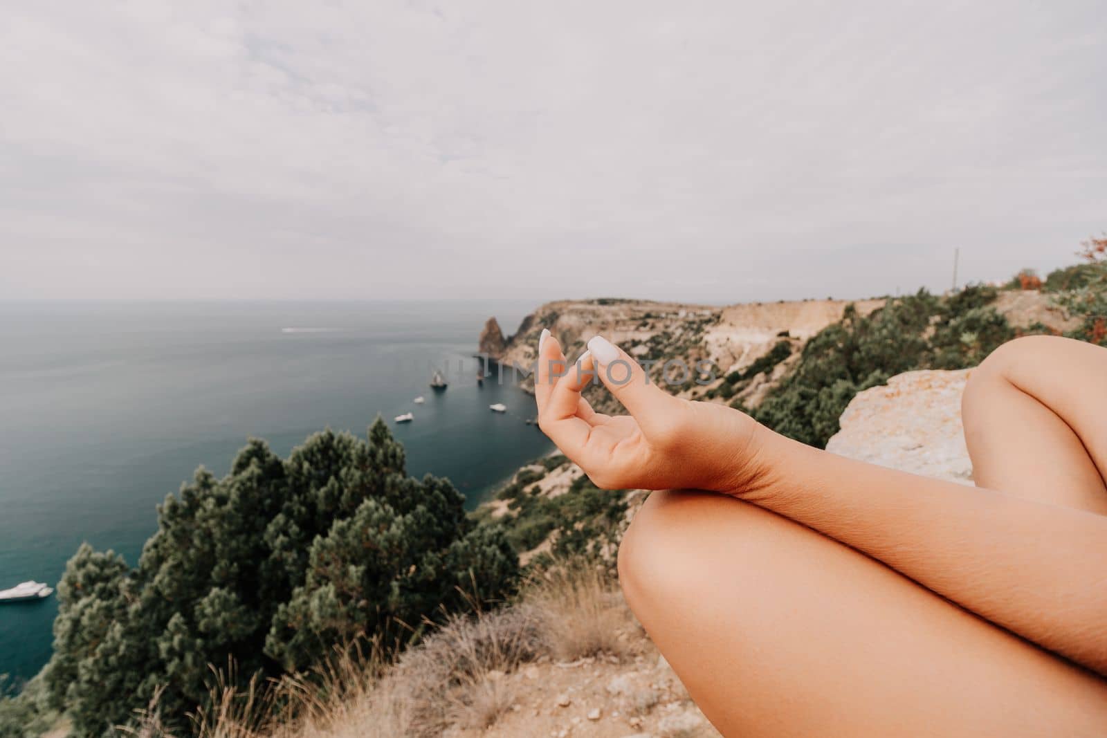Middle aged well looking woman with black hair doing Pilates with the ring on the yoga mat near the sea on the pebble beach. Female fitness yoga concept. Healthy lifestyle, harmony and meditation.