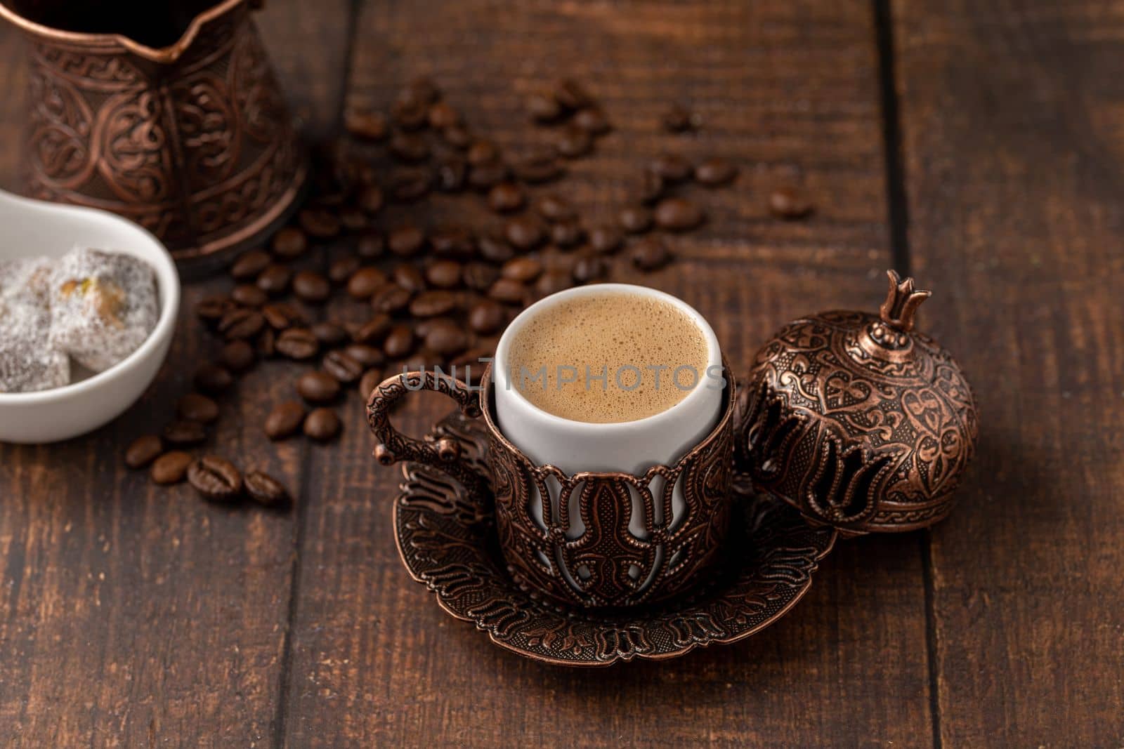 Turkish coffee in classic coffee cup with water and Turkish delight on wooden table by Sonat