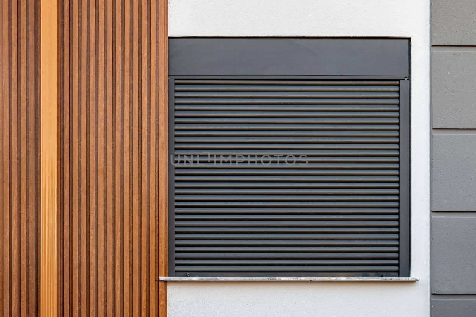 The building whose facade is covered with wooden patterned PVC panels and whose window is made of shutters