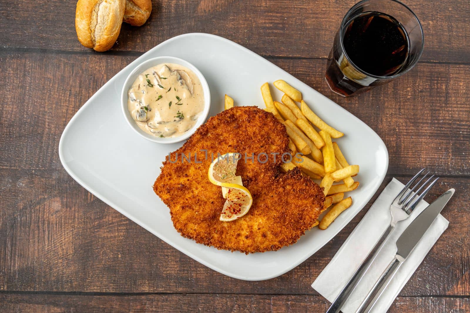 Chicken schnitzel with butter and potato salad on white porcelain plate by Sonat