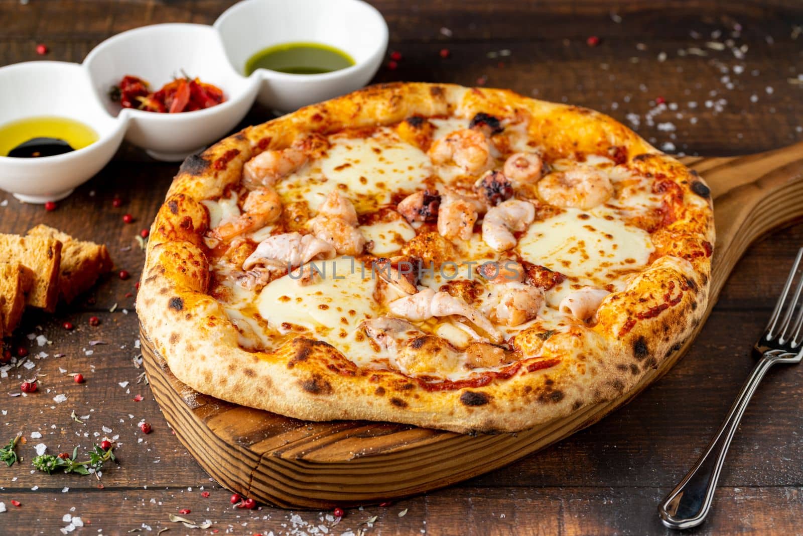 Italian pizza with shrimp and mozzarella on a cutting board by Sonat