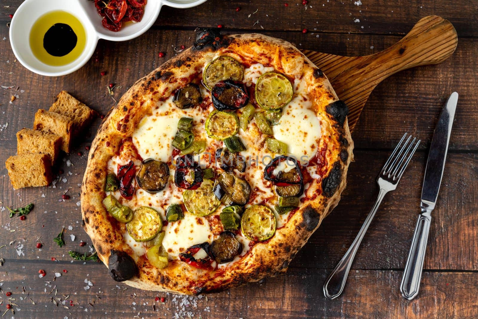 Vegetarian pizza with eggplant, zucchini and mushrooms on dark stone table by Sonat