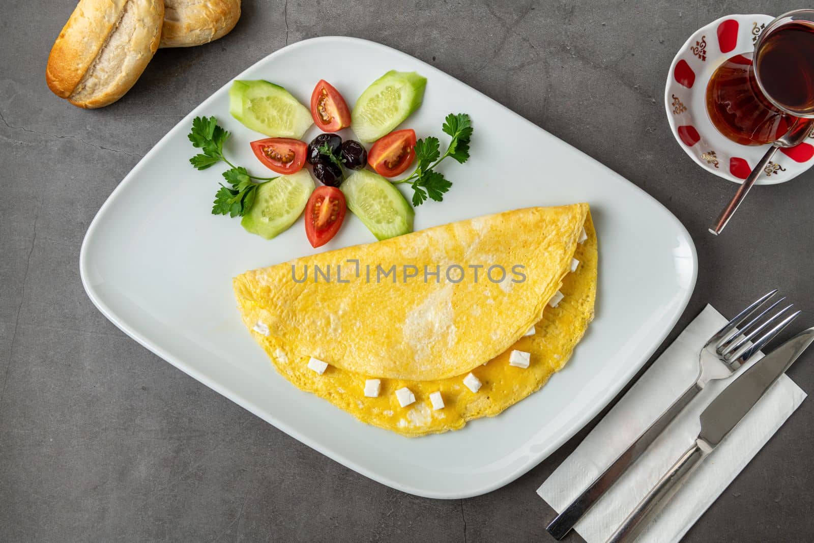 Feta cheese omelet with olives and tomatoes on a white porcelain plate