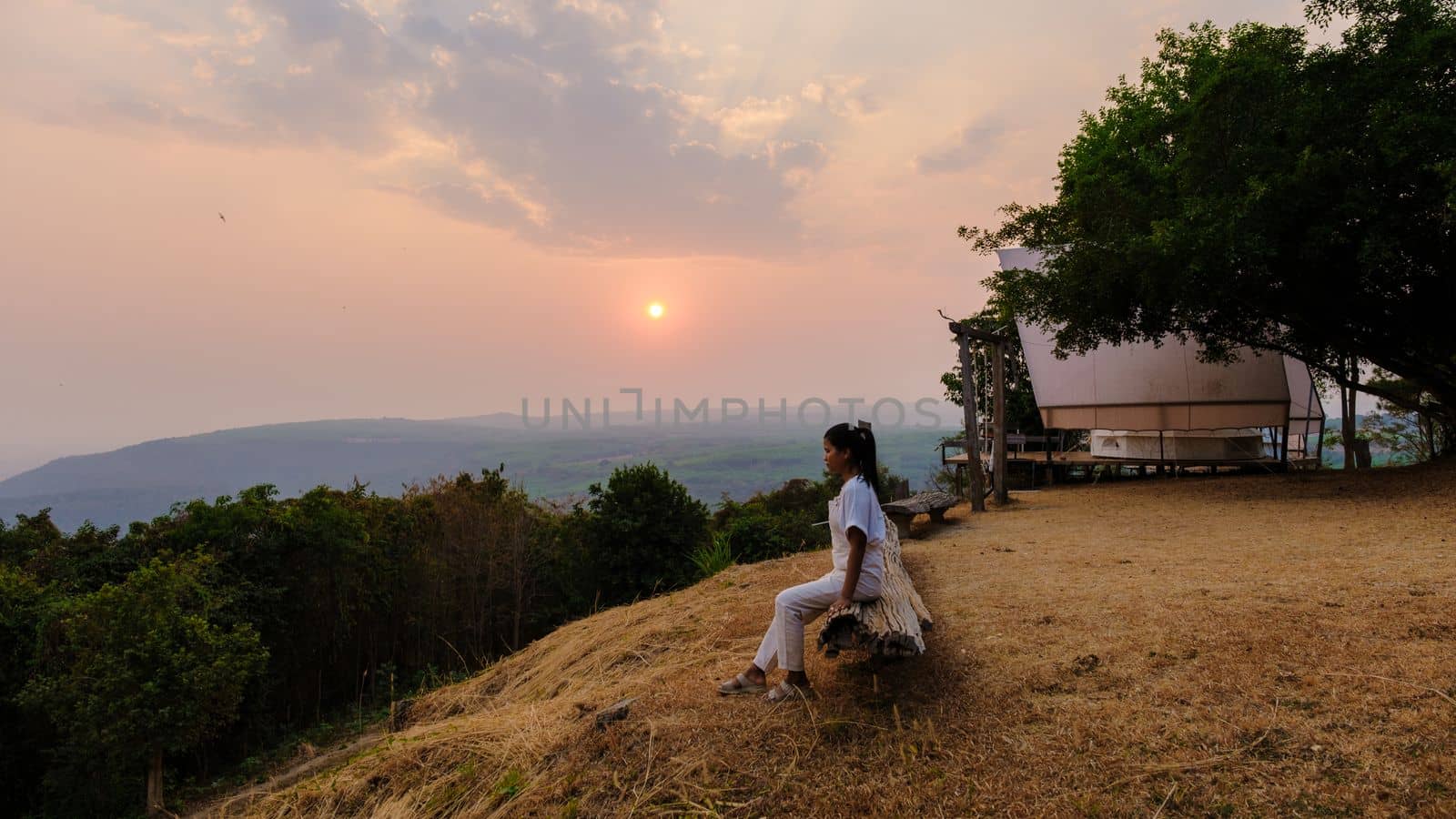 Sunset at a mountain camping in Phitsanulok Thailand. luxury glamping, Thai women watching sunset in the mountains of Northern Thailand