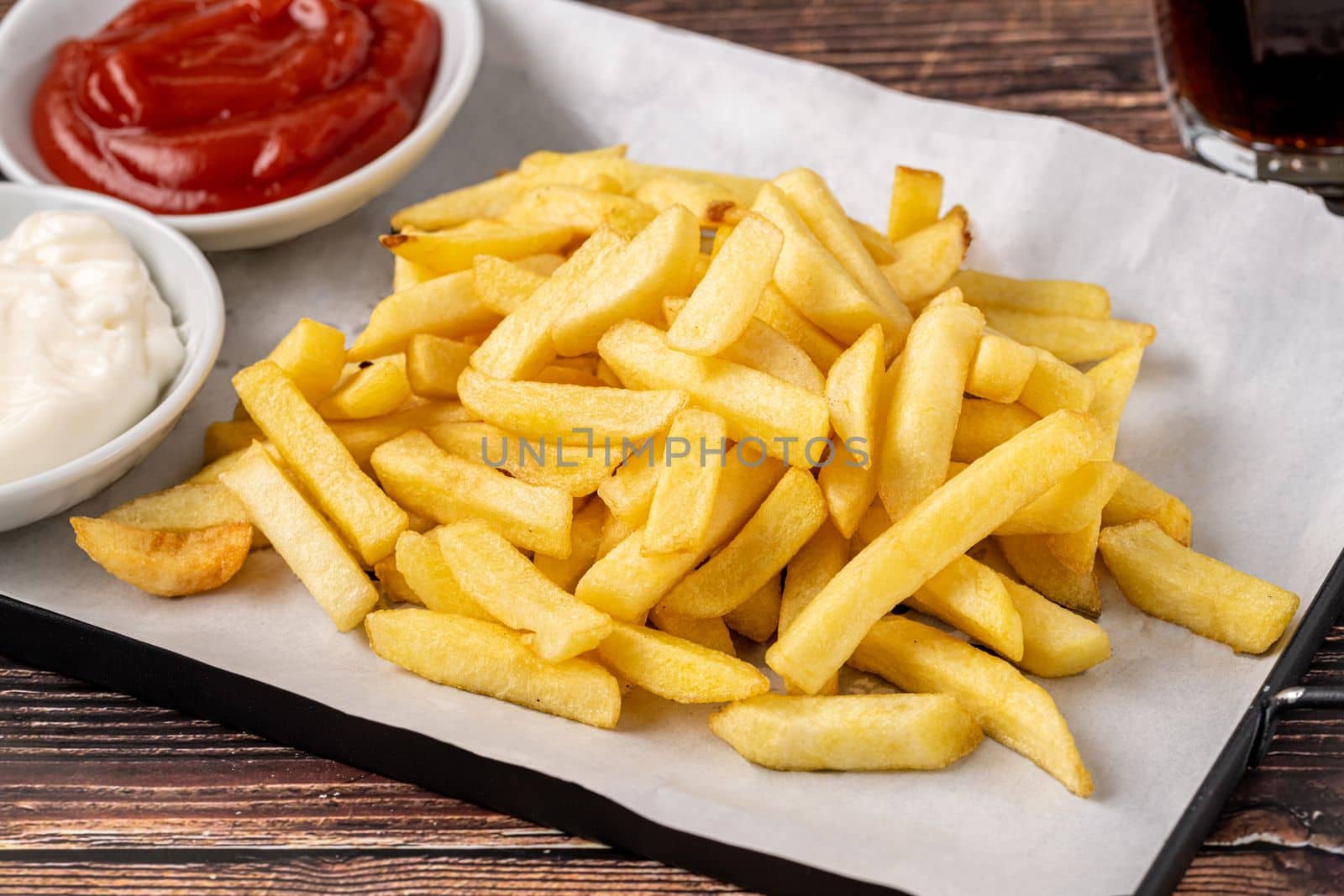 Golden French fries with ketchup and mayonnaise on wooden table by Sonat