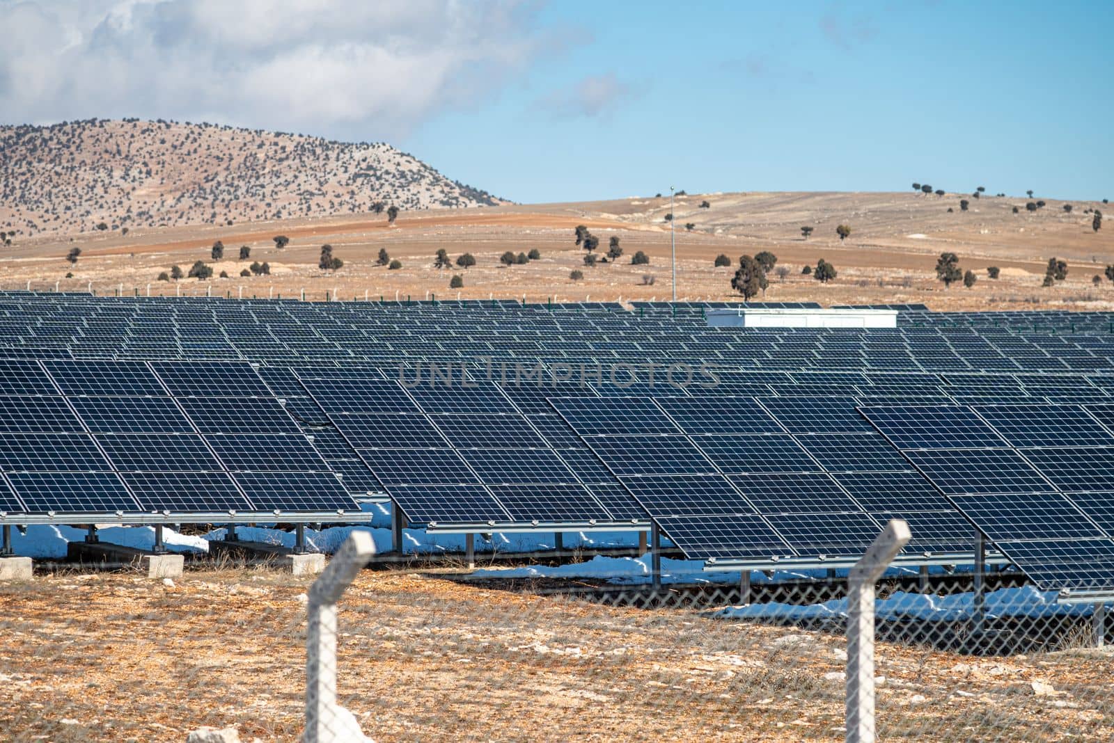 Solar field with fenced solar panels at sunset by Sonat