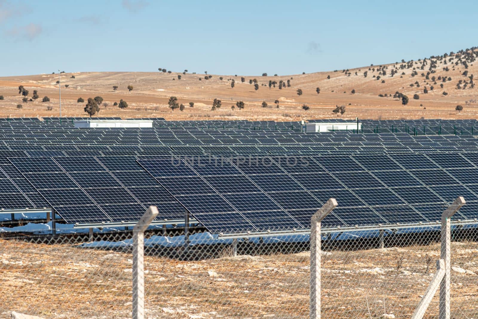 Solar field with fenced solar panels at sunset by Sonat