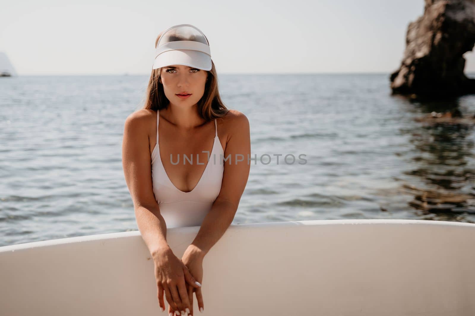 Woman sea sup. Close up portrait of happy young caucasian woman with long hair looking at camera and smiling. Cute woman portrait in a white bikini posing on sup board in the sea by panophotograph