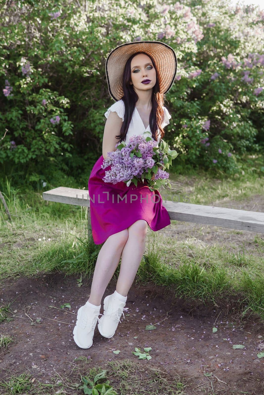 A fashionable girl with dark hair, a spring portrait in lilac tones in summer. Bright professional makeup