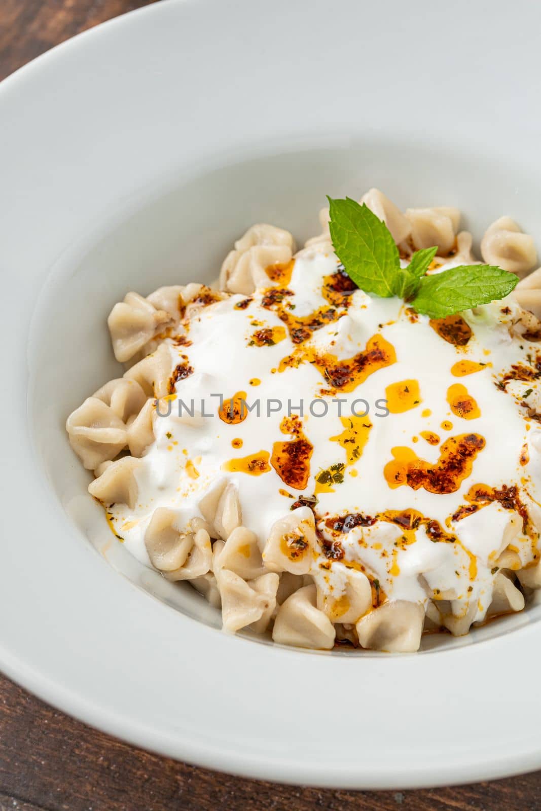 Kayseri ravioli or Kayseri Mantisi on a white plate on wooden table