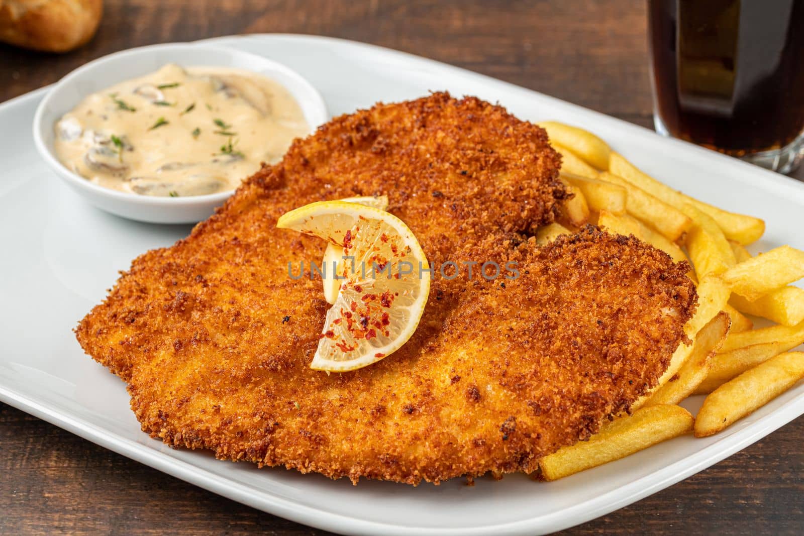 Chicken schnitzel with butter and potato salad on white porcelain plate