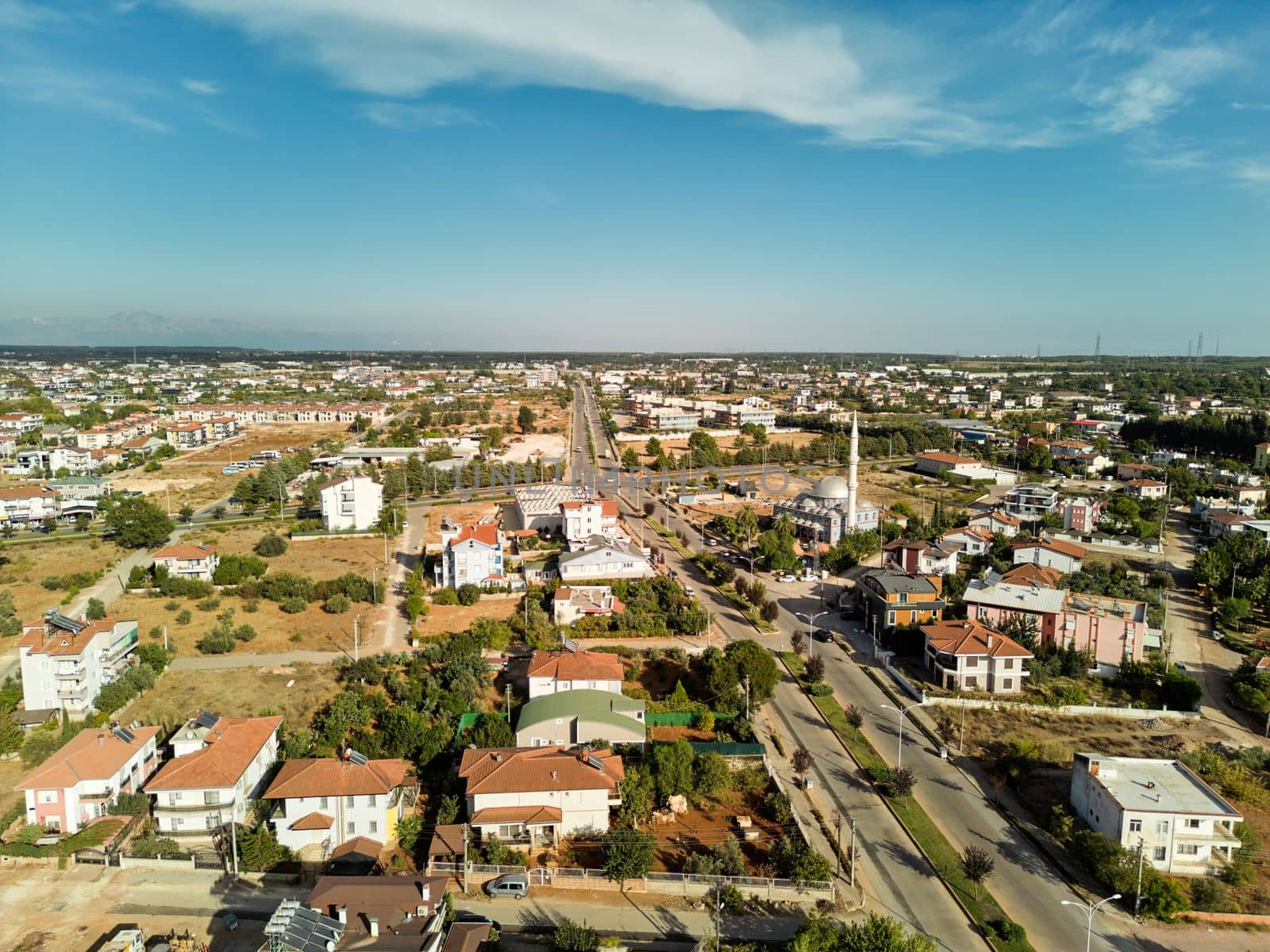 Aerial photograph of a town at sunset. A town with two-storey detached houses and a mosque